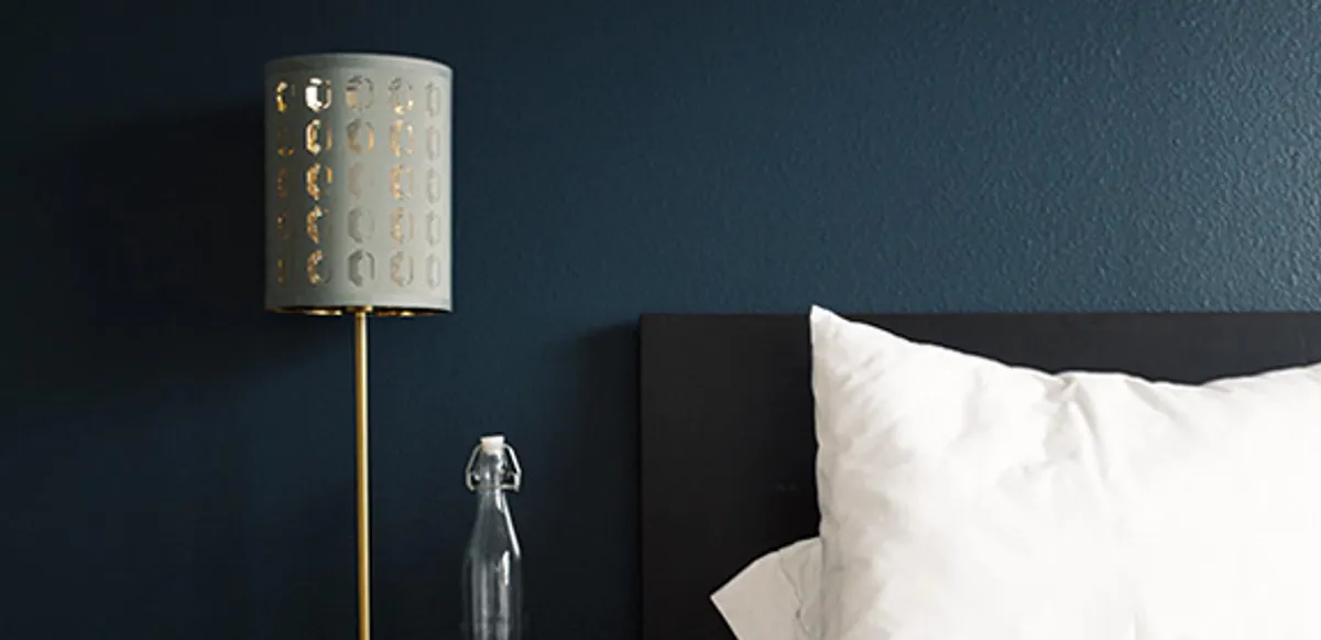 A dark bedroom lit by a single lamp